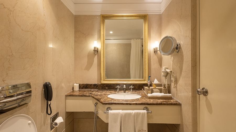 image of the sink with a rectangular mirror above it at our heritage balcony room -image of the heritage balcony room with sleek interiors and a a plush king size bed - The Claridges New Delhi