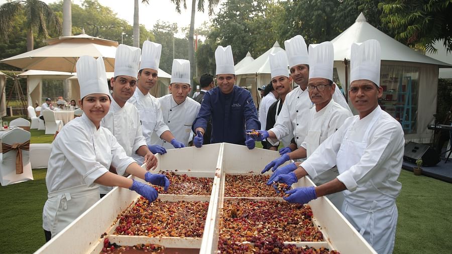 Image of people posing for a photo while preparing a cake in the open, spacious garden at The Claridges New Delhi
