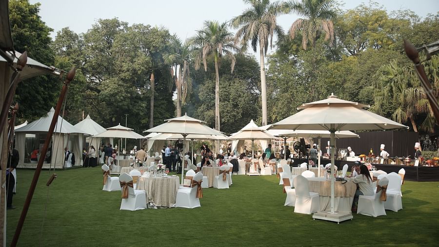 Image of the spacious garden at The Claridges New Delhi, featuring an open area with a clear sky, surrounded by large trees