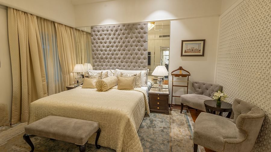 Superior Room at The Claridges New Delhi, featuring a cosy bed with bedside lights and two chairs arranged in the corner