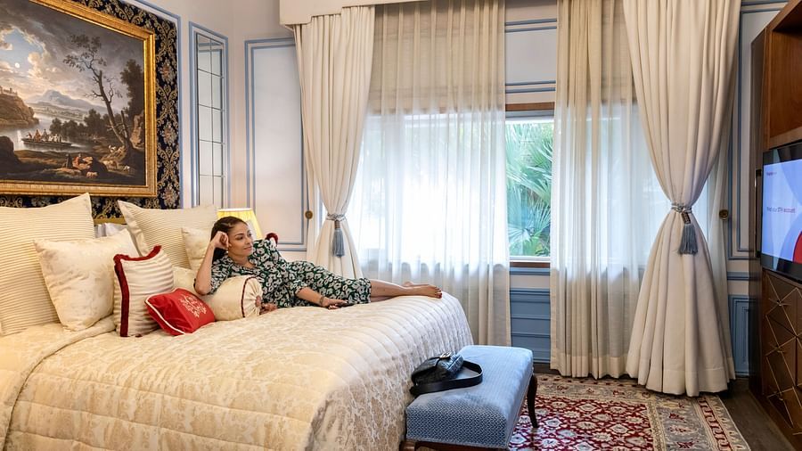 image of a woman relaxing on the plush king size bed at the willingdon crescent suite - The Claridges New Delhi