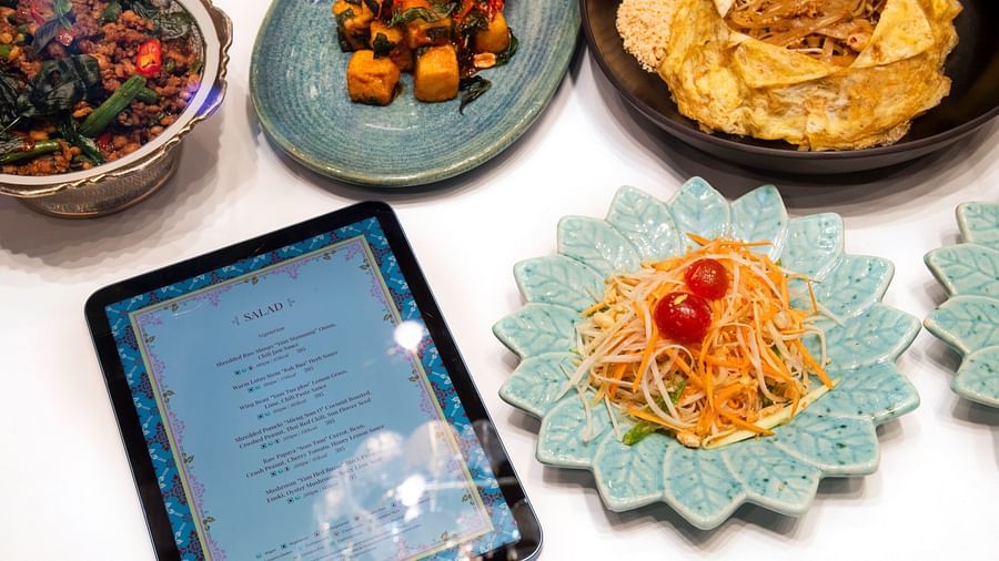 image of a tablet with the menue of the pickwick multi cuisine restaurant with delicious dishes served around it - The Claridges New Delhi