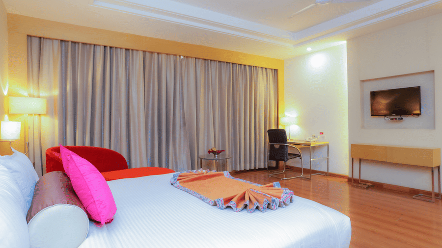 A well-appointed hotel room with a large bed, featuring dark curtains and bright accents at The Conway, Meerut.