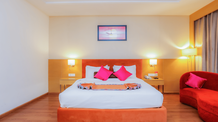 A comfortable hotel bed with a stylish headboard and warm lighting, ready for guests at The Conway, Meerut.