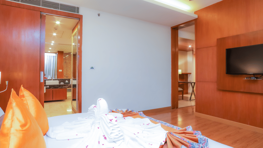  A well-decorated hotel suite bedroom with a large bed and a wall-mounted television at The Conway, Meerut.