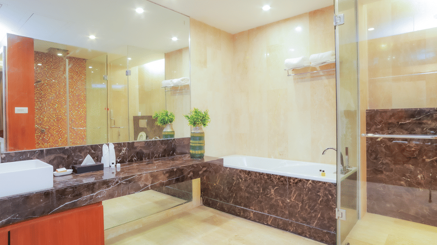 A luxurious hotel bathroom with a large mirror, double sink, and glass shower enclosure at The Conway, Meerut.