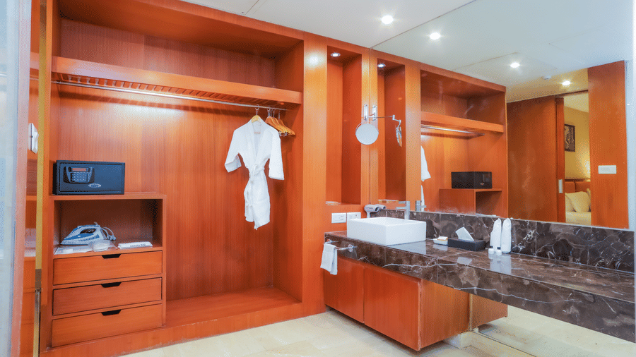 A spacious hotel walk-in wardrobe with hanging space, drawers, and a dressing mirror at The Conway, Meerut.