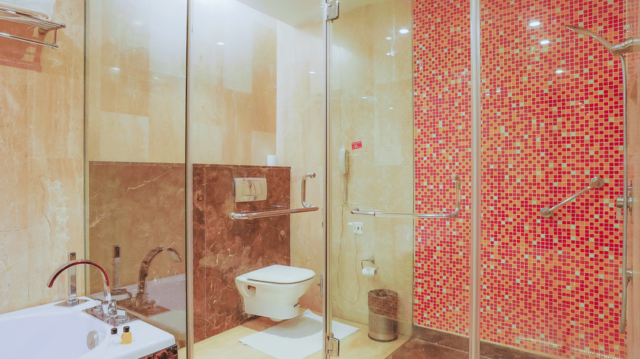 A contemporary hotel bathroom featuring a glass shower and stylish patterned wall tiles at The Conway, Meerut.
