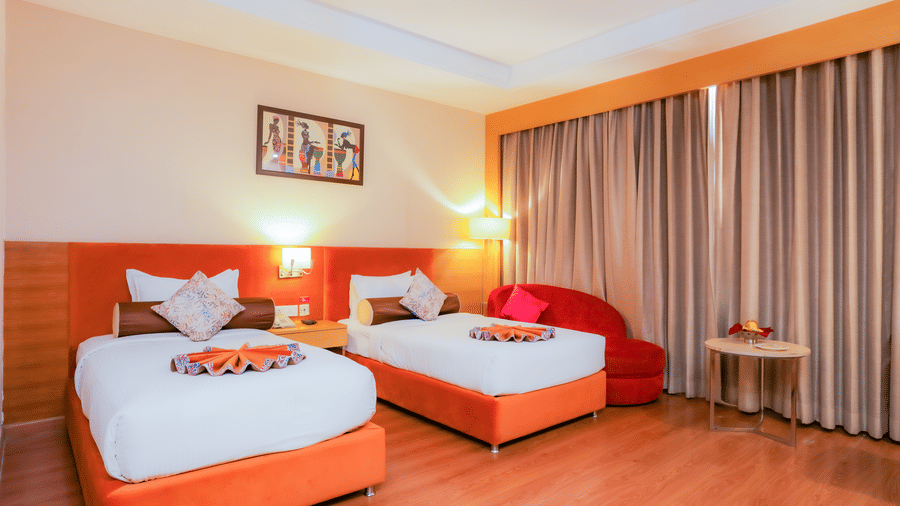 A comfortable hotel room with two single beds, bright decor, and wooden flooring at The Conway, Meerut.