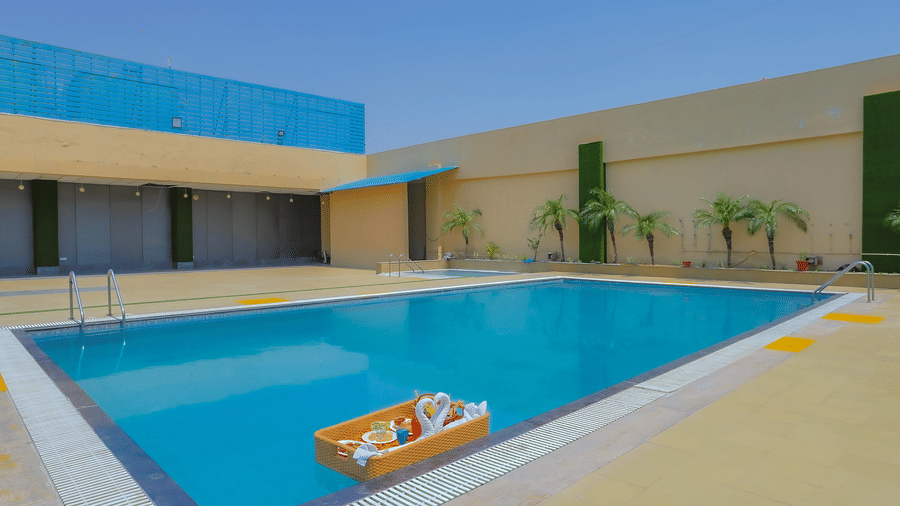 The inviting outdoor swimming pool featuring a white inflatable raft, surrounded by paved areas at The Conway, Meerut.