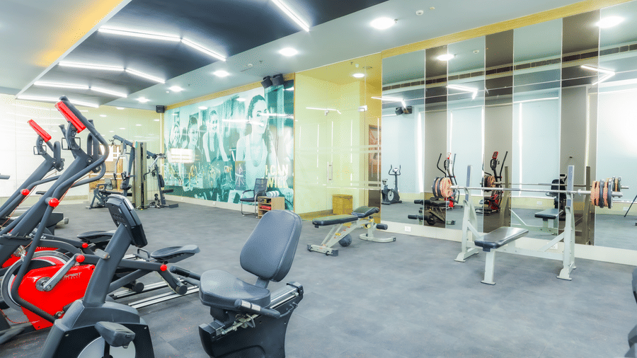A modern gymnasium showcasing a range of exercise equipment and mirrored walls at The Conway, Meerut.