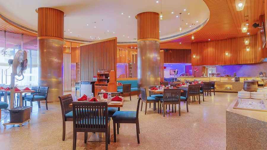 A spacious restaurant dining area with varied seating and warm lighting at The Conway, Meerut.