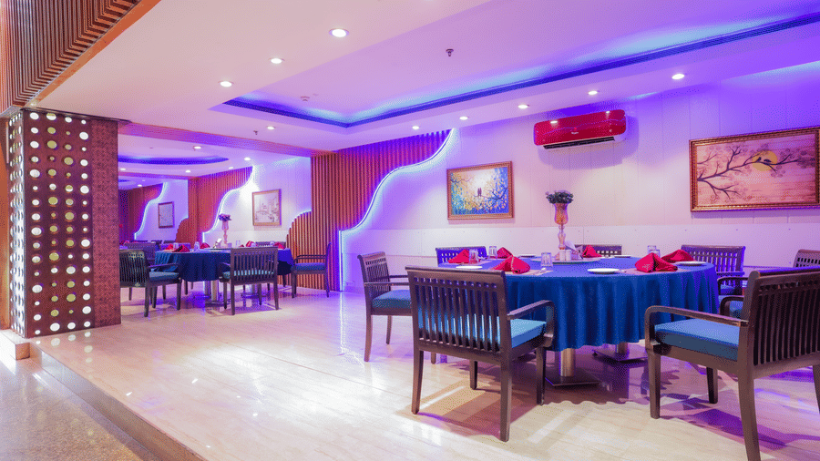 A restaurant dining area illuminated with striking purple and blue ambient lighting at The Conway, Meerut.
