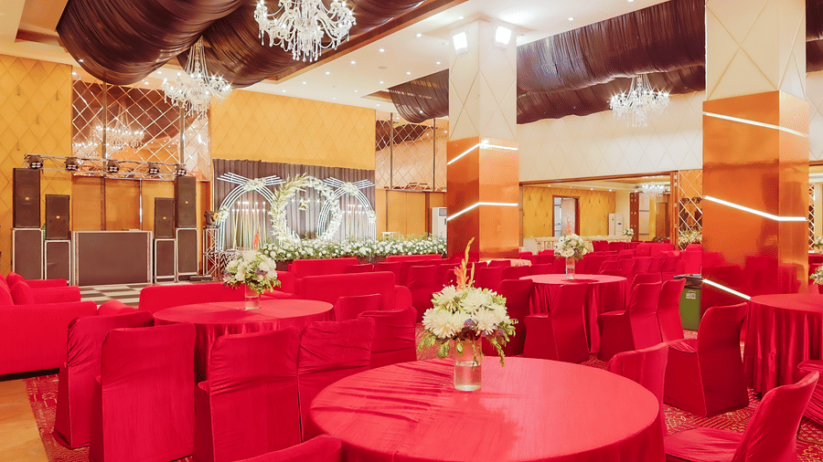  Close-up of red-draped tables with elegant floral arrangements in a banquet setting at The Conway, Meerut.