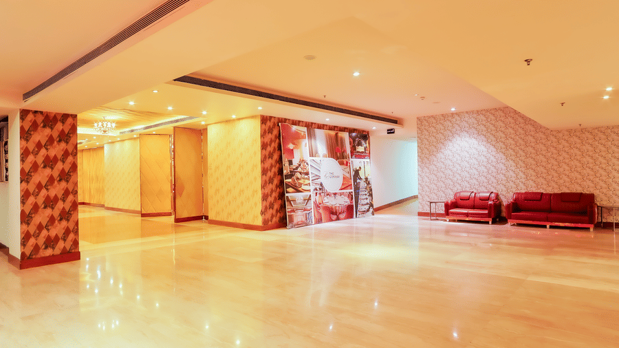 A wide view of an empty hall space with high ceilings and decorative wall panels at The Conway, Meerut.