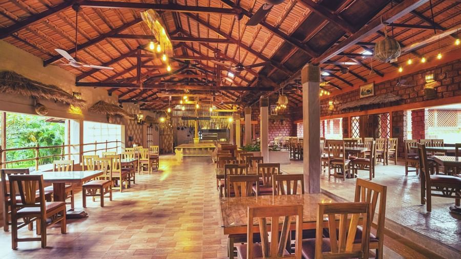 An interior shot of the restaurant at The Copper Edge - Eco Resort, Coorg, with a full view of the dining area and outside view.