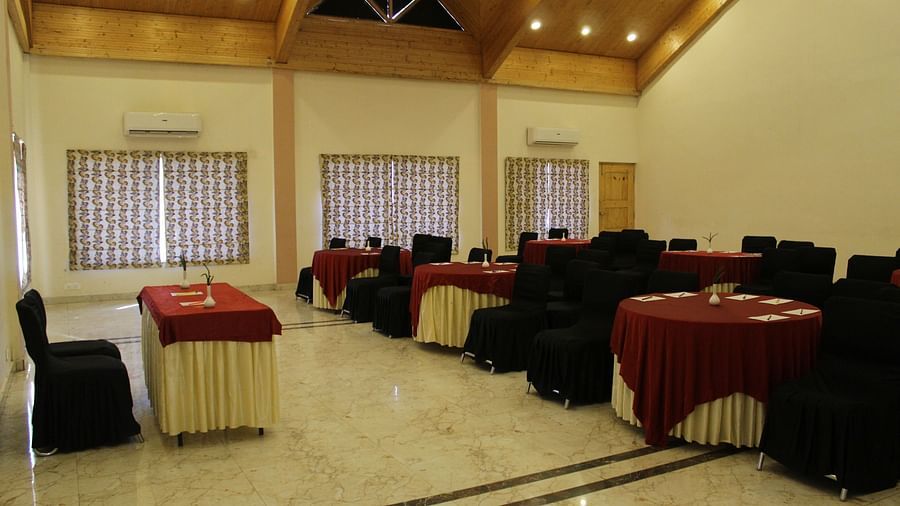 Side angle of the banquet hall, showcasing bright lighting, well-arranged tables, and a polished floor at Dagshai Manor Kasauli - Inde Hotels.