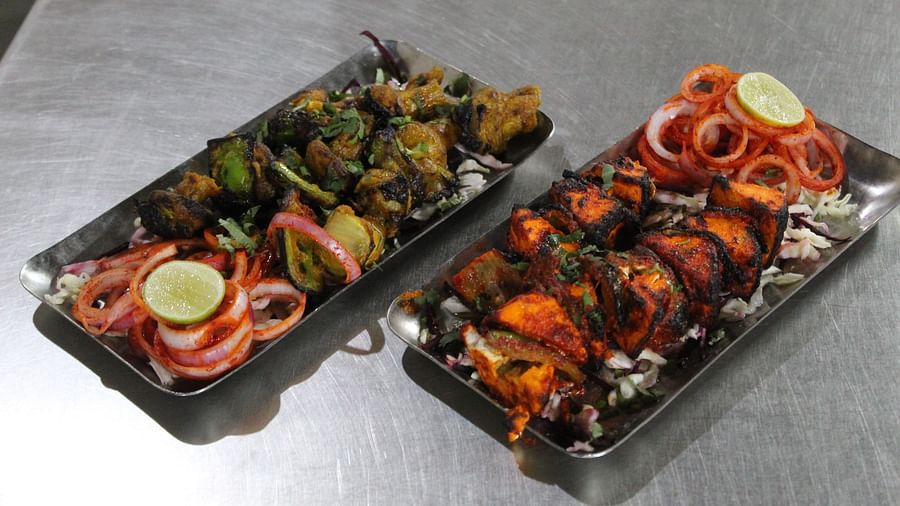 Two platters of grilled tandoori dishes on a stainless steel counter top at Dagshai Manor Kasauli - Inde Hotels.