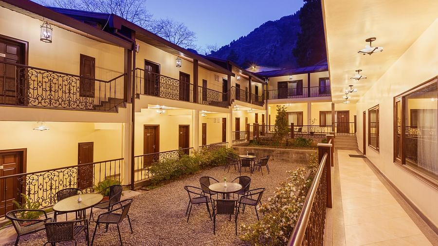 a well lit seating area in the hotel interior with tables with chairs in clusters - The Earl's Court, Nainital