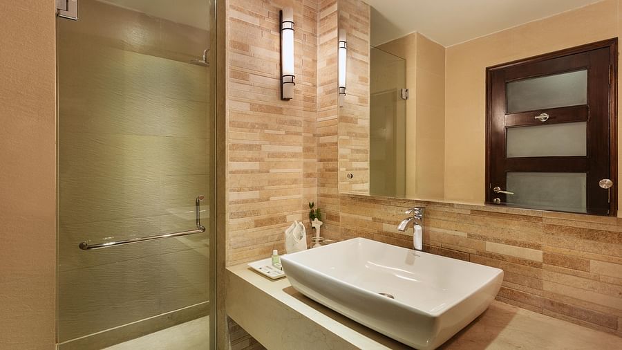 An image of a bathroom with shower screen, sink and faucet, and a mirror attached to the wall - The Earl's Court, Nainital