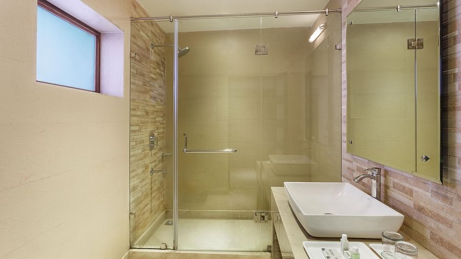 An image of a bathroom with shower screen, sink and faucet, and a mirror attached to the wall - The Earl's Court, Nainital