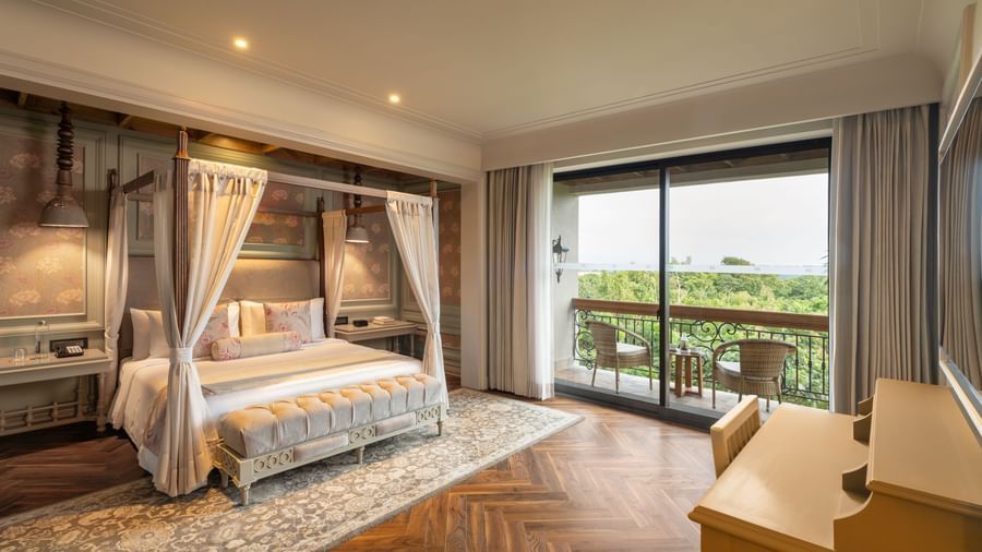 Full-view shot of the bedroom at the Evren Suite featuring wooden flooring and a balcony that opens to the verdant views of the frest at The Evren, Vagator.
