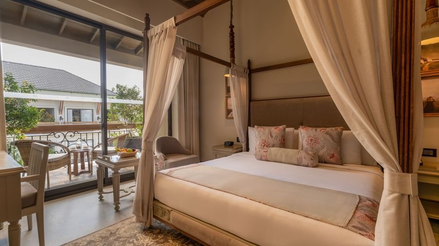A plush double bed in the Premium Room at The Evren, Vagator, with a balcony beside it featuring a sit-out area.