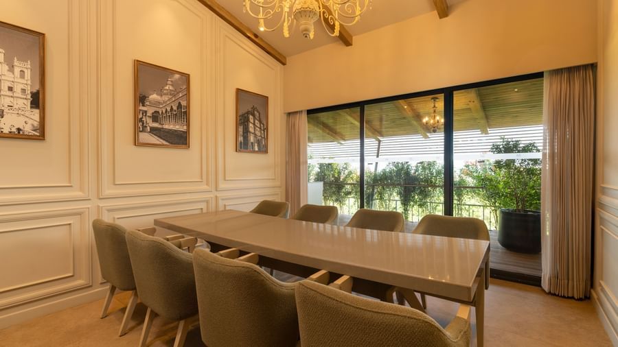 A brightly-lit boardroom at The Evren, Vagator, featuring a long conference table with a window behind it overlooking the lush green lawns.