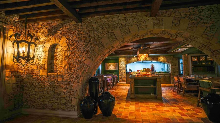 A dimly-lit entrace to the Mila restaurant at The Evren, Vagator, featuring a arched wall made of stone.