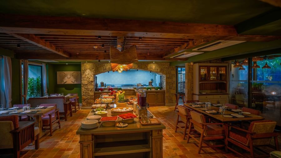 Full view of the Mila Restaurant featuring a buffet table in the middle along with well-arranged dining tables around it at The Evren, Vagator.