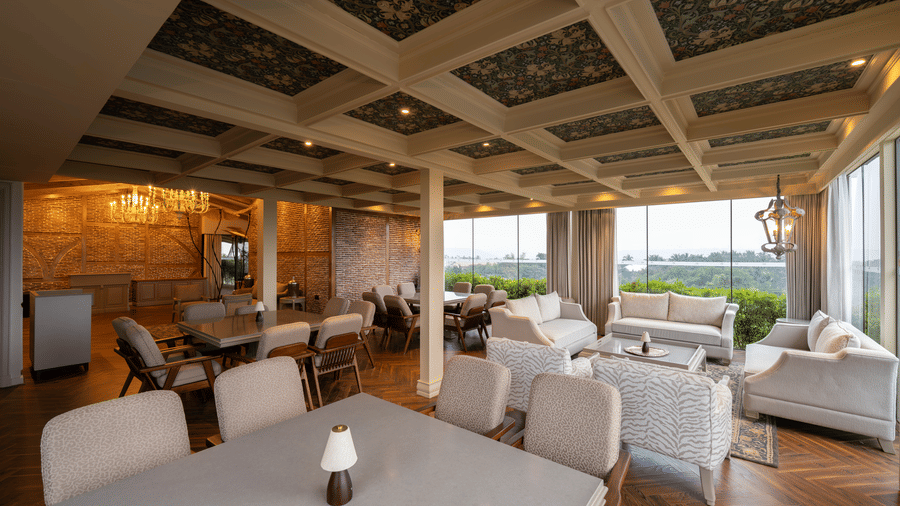 The executive lounge area at The Evren with arranged dining tables, chairs, patterned ceiling panels, and large windows.