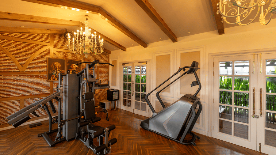 A fitness room at The Evren with exercise machines, wooden flooring, and windowed walls.