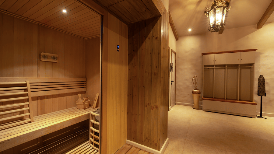 A spa sauna area at The Evren with a wooden steam cabin, tiled flooring, benches, and a warmly lit corridor.