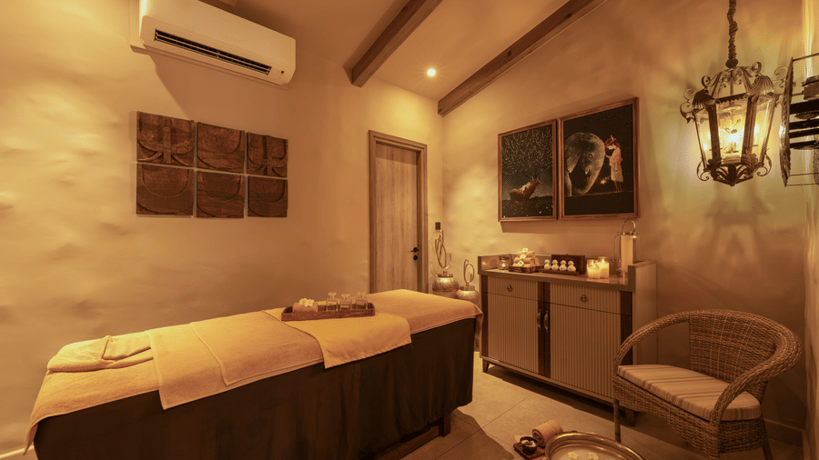 A spa room at The Evren with massage beds, storage cabinets, wall art, and an armchair.