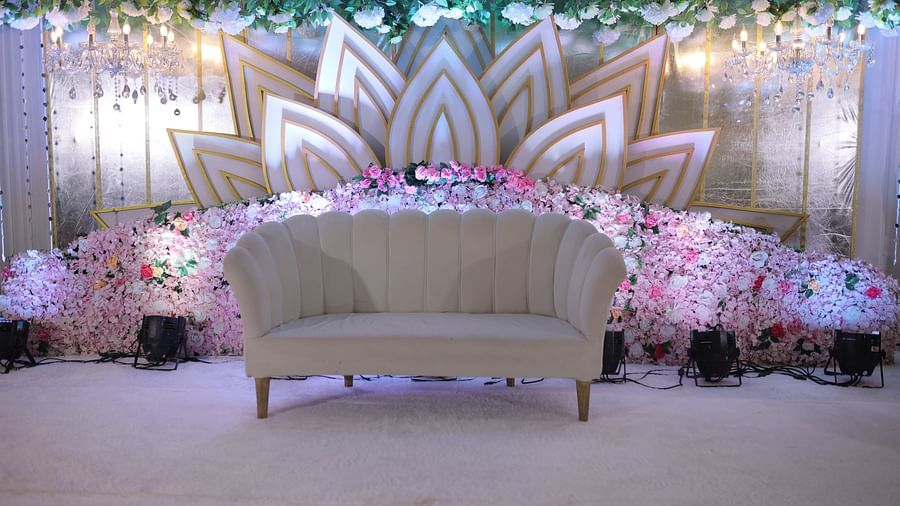 Empty love seat on carpet before a backdrop of lotus petals, and flowers, and soft lights, likely for a wedding reception - The Grand Legacy Resort and Spa