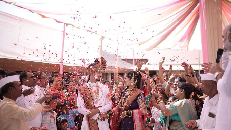 Guests shower a wedding couple with flower petals as they walk under a decorated canopy, signifying blessings and joy - The Grand Legacy Resort and Spa