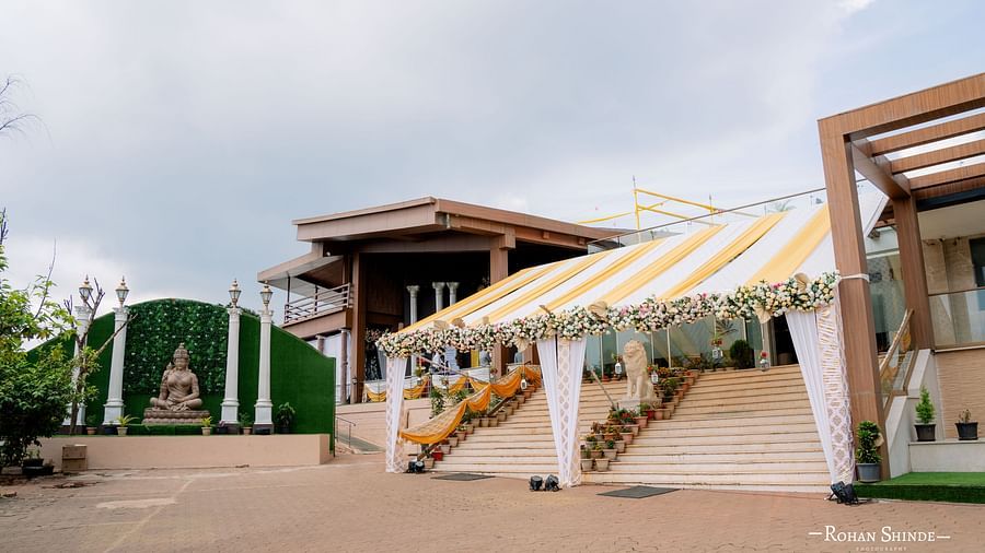 An outdoor wedding venue with a decorated entrance, tents, and palm trees under a partly cloudy sky, suggesting a daytime event - The Grand Legacy Resort and Spa