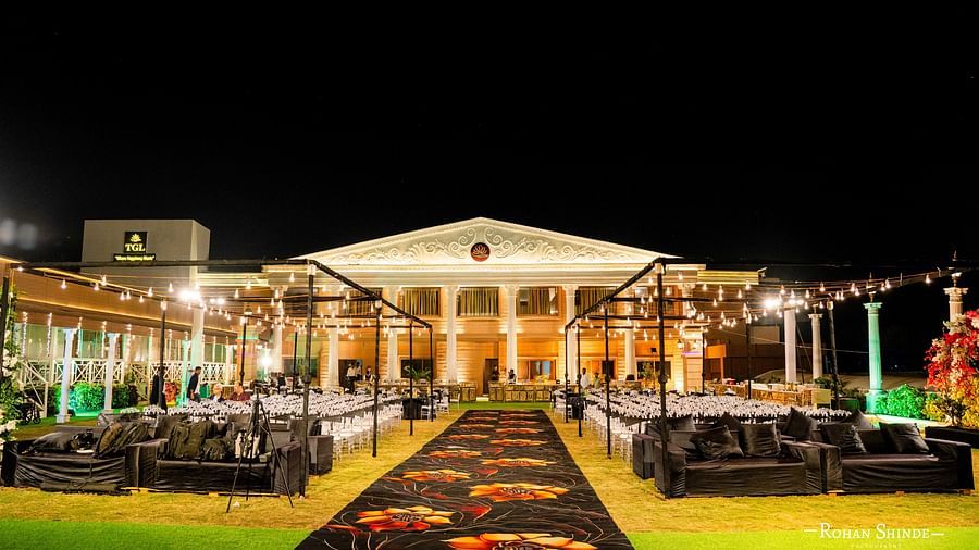 A grand wedding reception at night. The illuminated venue features a long walkway, tables, and chairs, ready for guests to celebrate - The Grand Legacy Resort and Spa