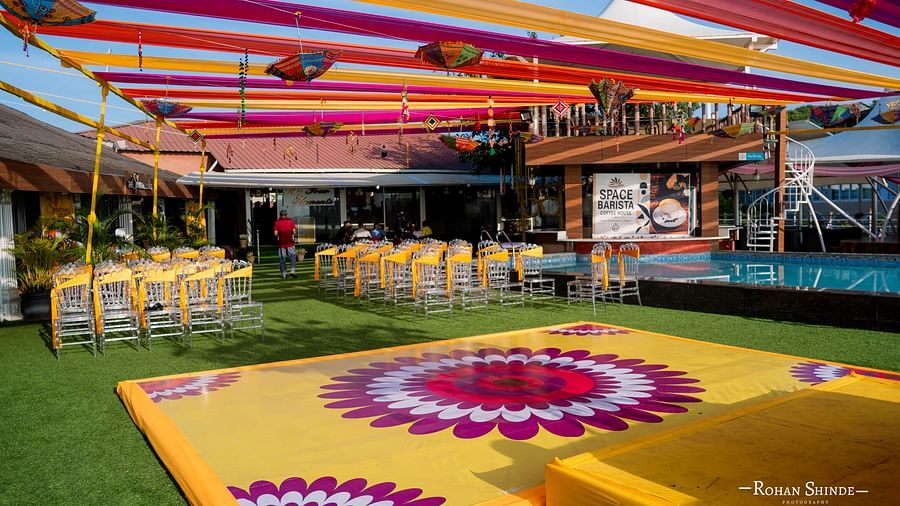 A colourful wedding venue with a patterned dance floor, draped fabrics overhead, and set tables, suggesting a lively reception setting - The Grand Legacy Resort and Spa