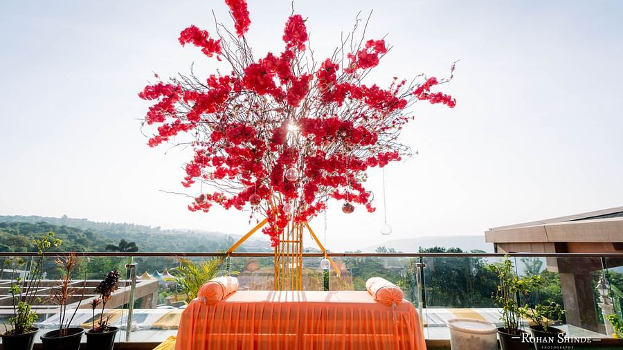 A vibrant red floral arrangement atop a decorated structure, possibly for a wedding, set against a backdrop of a building and natural landscape - The Grand Legacy Resort and Spa