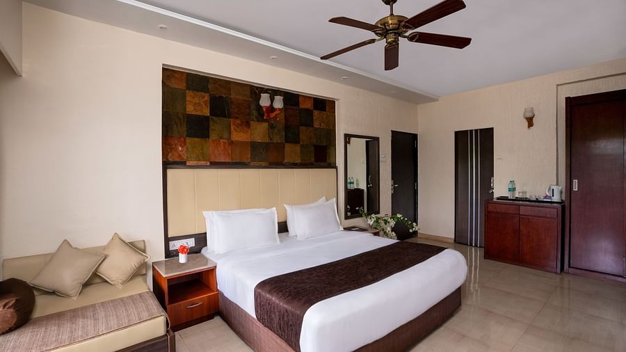 A shot of a king size bed in a spacious room and a couch along with various wall decor | 