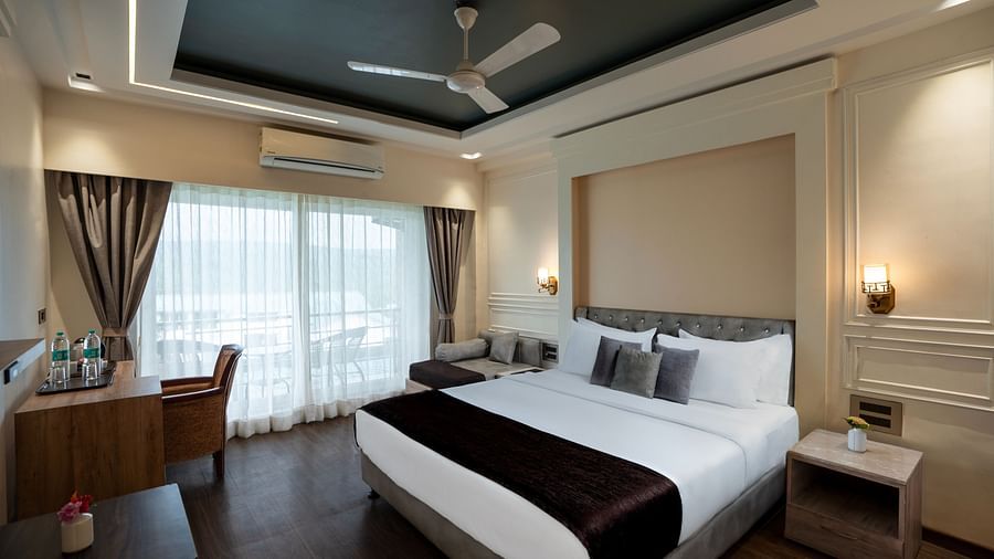A spacious room with neutral-toned walls, a large bed and large windows offering natural light. | The Grand Legacy Resort and Spa 