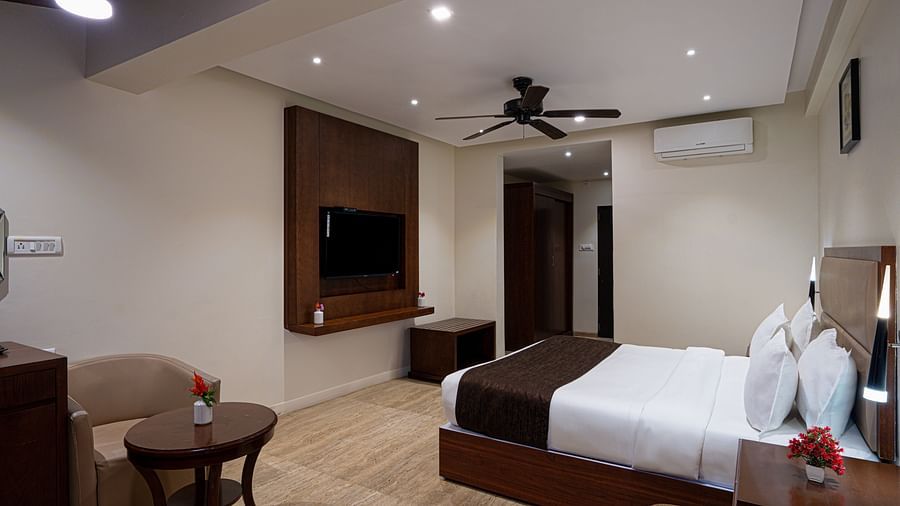Image of a spacious room with a king size bed, flat screen television, sofa , a round table and other furnishing | The Grand Legacy Resort and Spa