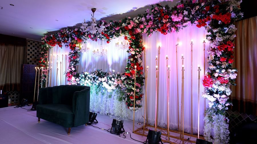 A stage set up for bride and groom featuring a sofa and at the background the wall is decorated with fabric pieces and flowers at The Grand Legacy Resort & Spa