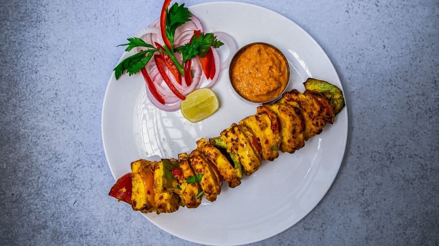 A white plate of neatly arranged appetiser sided with a sauce, and cut vegetables  at The Hamuse Hotel, Kodaikanal,