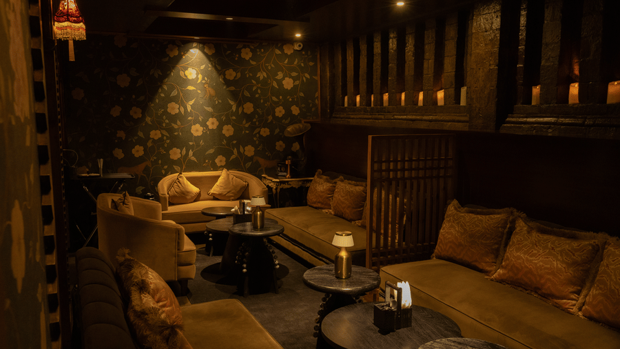 A dining space with sofas, tables, and a lamp. | The Heritage Club, Tripura, Castle, Shillong
