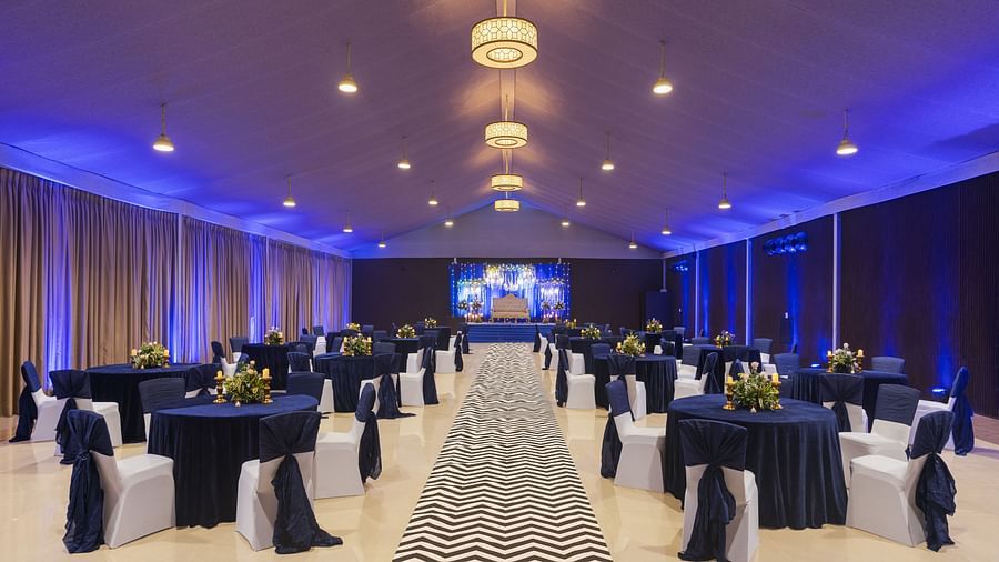 a pathway with clusters of tables and chairs on each side of the pathway and chandeliers lighting up the pathway throughout - The Hideaway Banquets & Lawns, Greater Noida