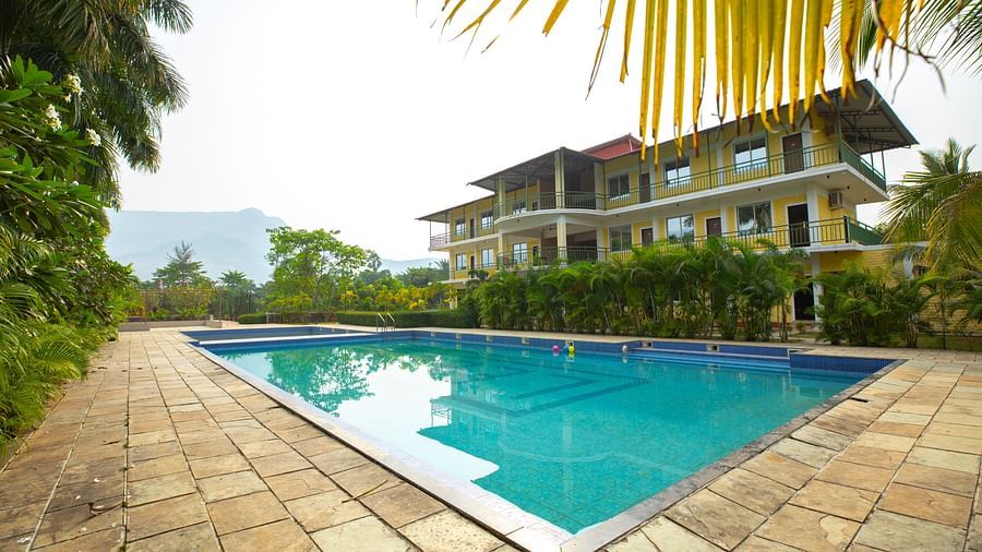 Overview of swimming pool with blue water at The Kanila Resort surrounded by trees.