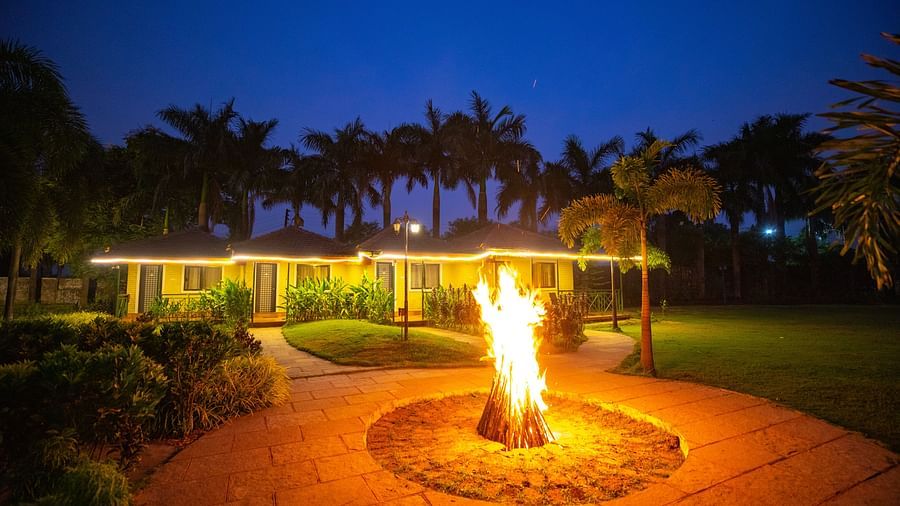 Bonfire at The Kanila Resort with backdrop of trees and blue sky.