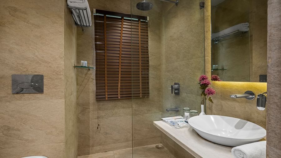 a washroom with a washbasin and toiletries on the right side and a western style toilet on the left - The Manor, Kashipur